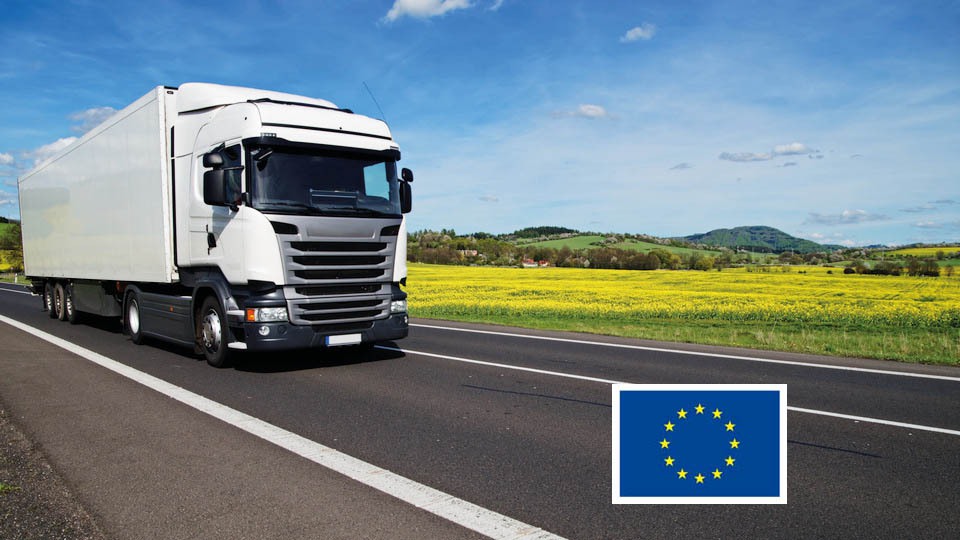 Lastbil kör på väg och en EU-logga