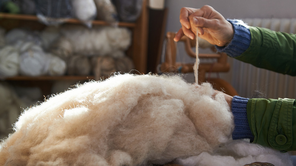 handmade manufacturing yarns from natural sheep wool, female hands closeup