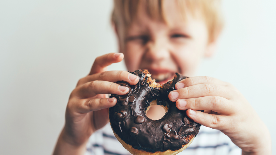Closeup of a bitten chocolate donut in the hands of a child