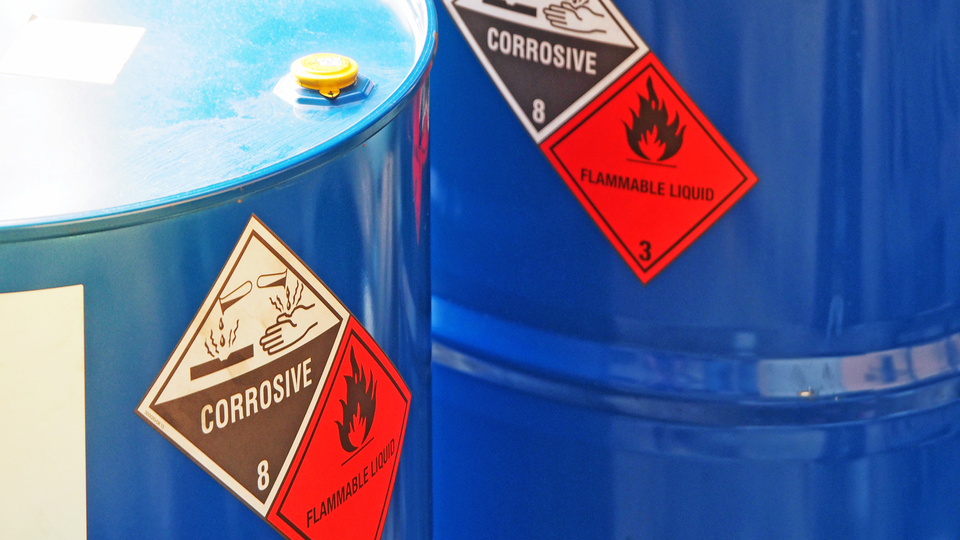 Close-up shot of blue color hazardous dangerous chemical barrels ,have warning signs on them warning about flammable liquid and corrosive.