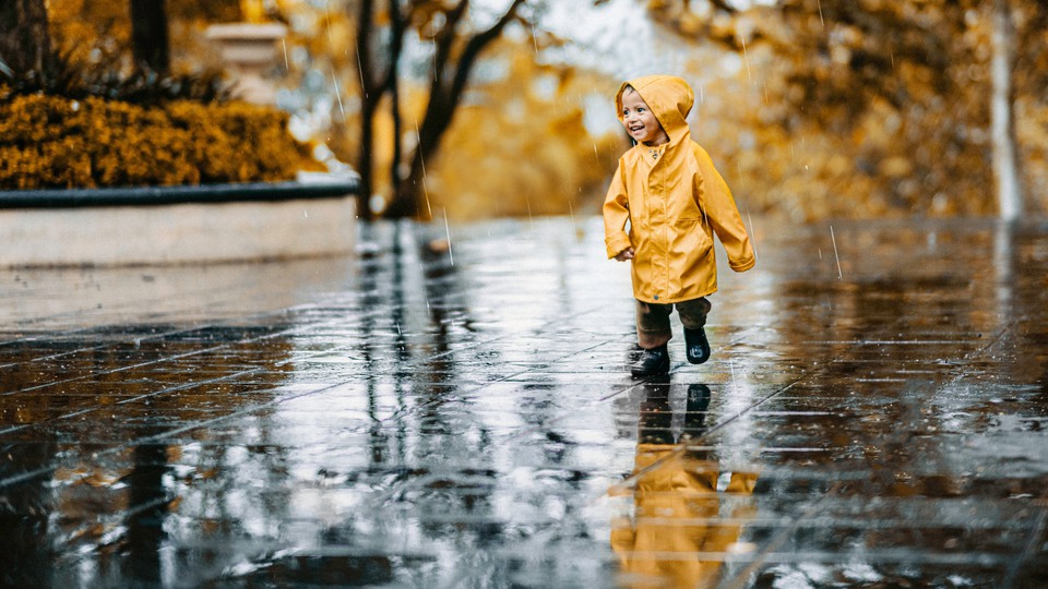 Barn i regnjacka leker i regn